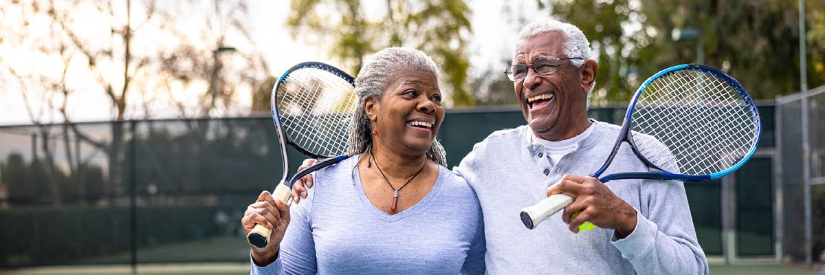 Two senior citizens having fun playing tennis